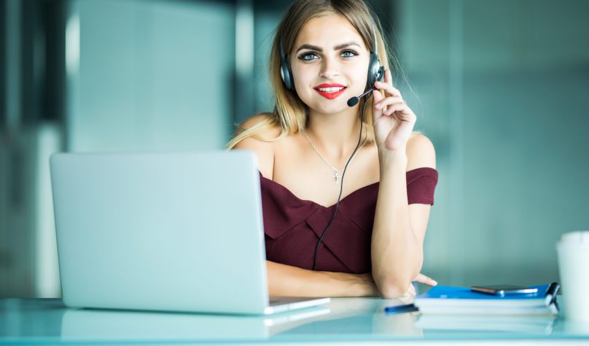 Portrait of happy smiling female customer support phone operator at workplace.